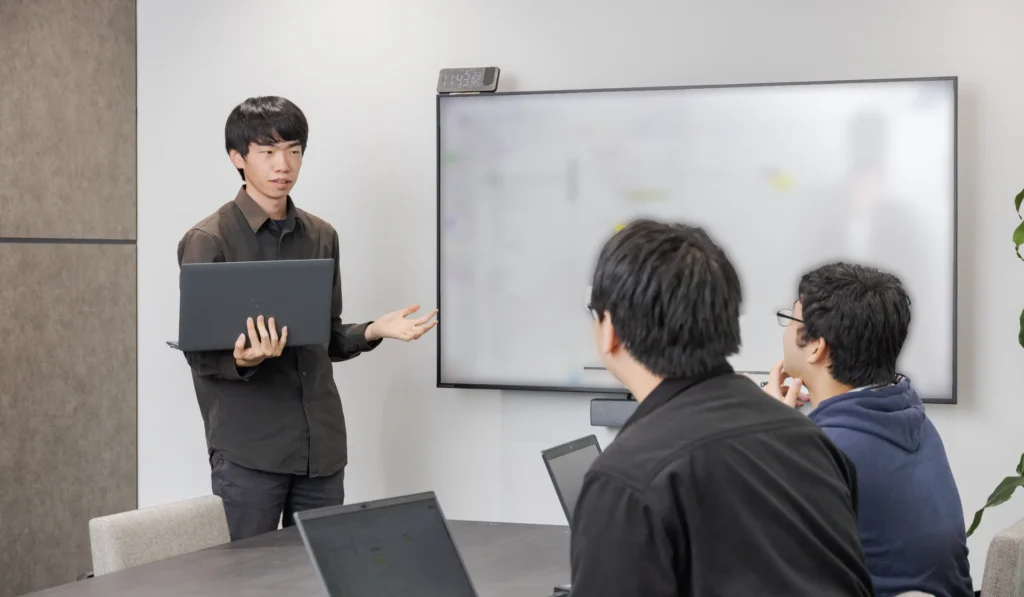 ホワイトボードで提案を説明するワードシステムのエンジニア